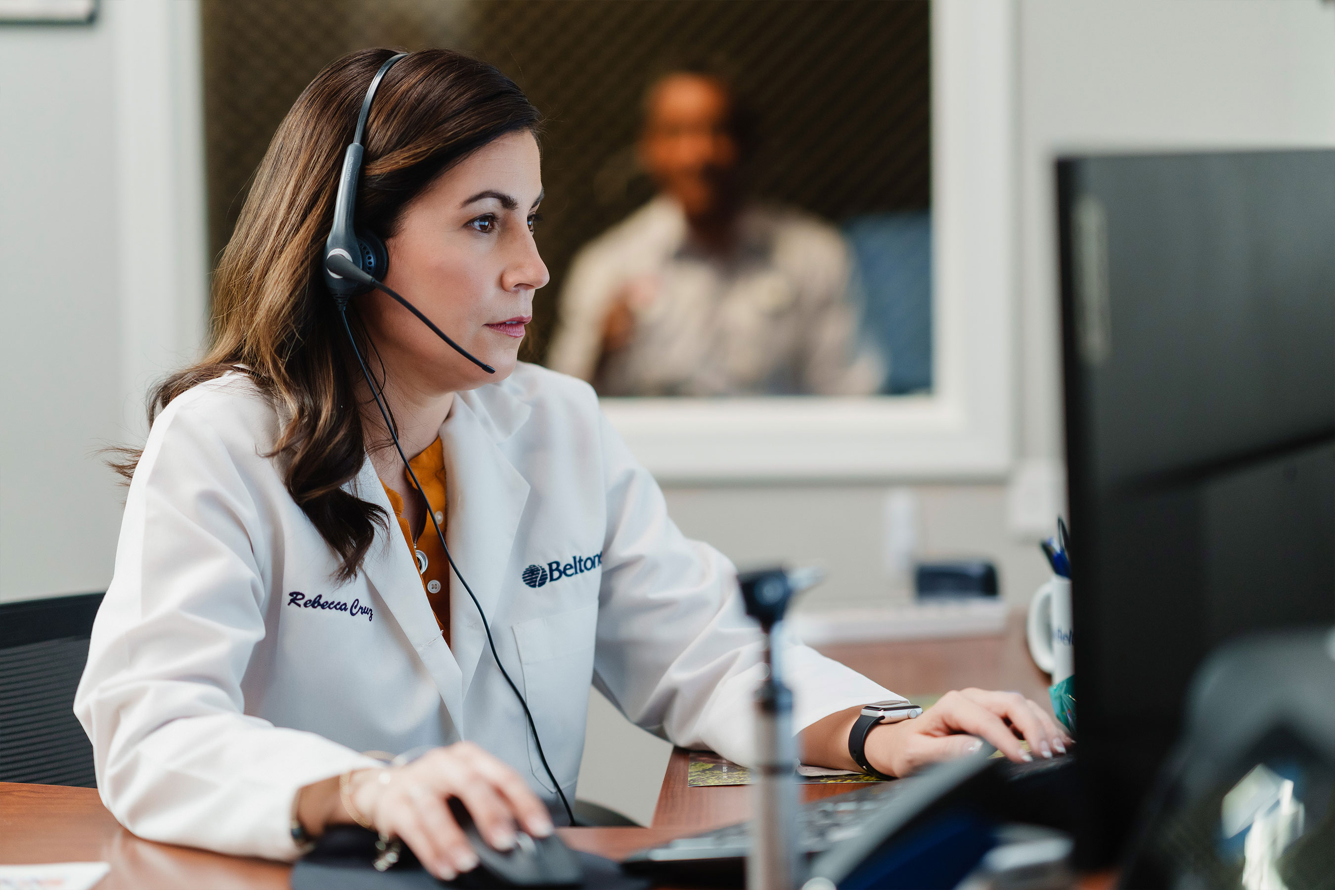 Patient sitting in a sound booth during his hearing screening with a Beltone hearing care professional.