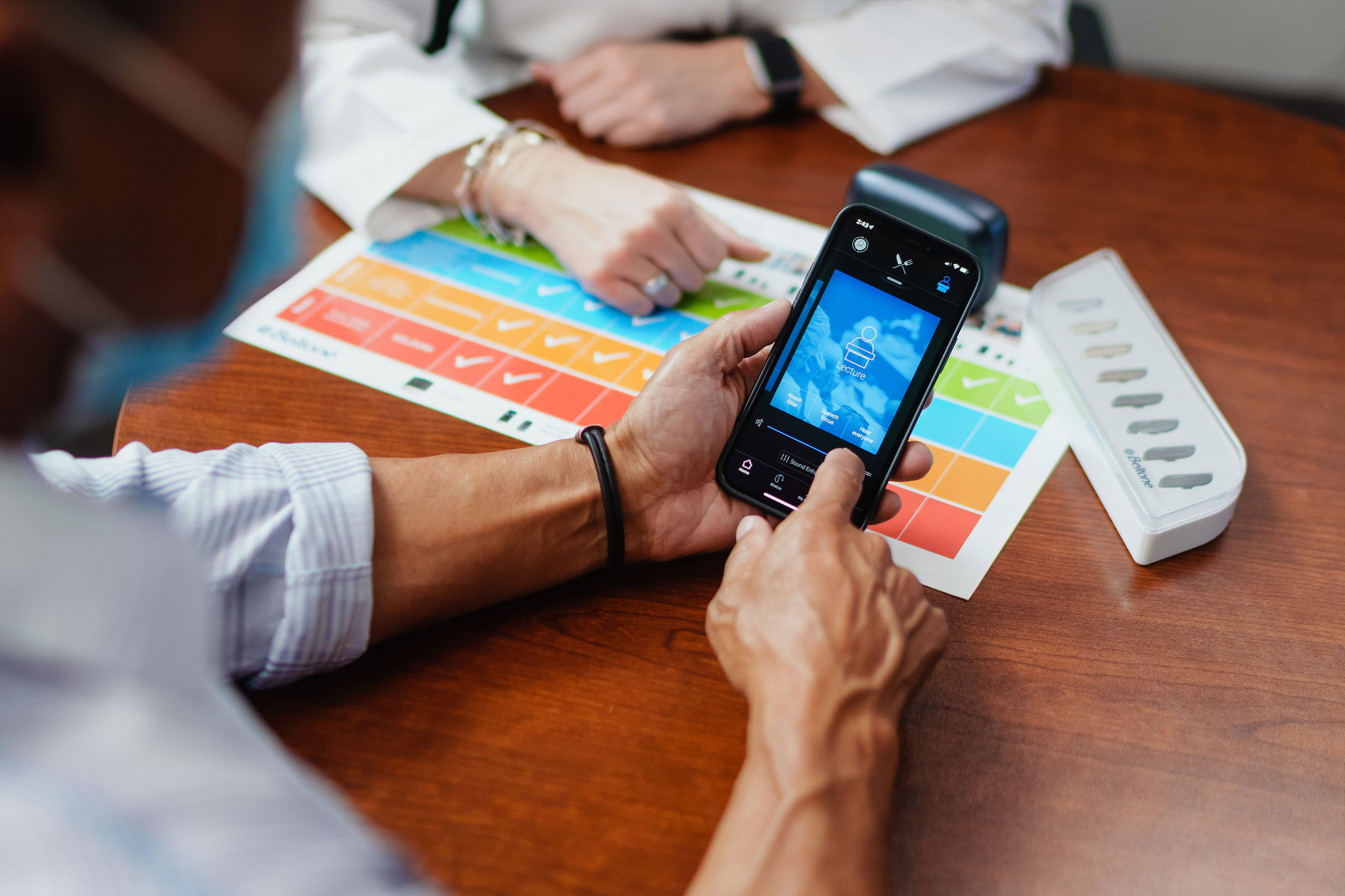 Beltone hearing care professional helping her patient use the Beltone HearMax app so he can control his hearing aids and much more.